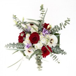 To a florist in Harlesden, this bouquet signifies the artful convergence of tradition and contemporary flair. Spirals of lush red roses sit as the proud focal point, surrounded by pristine white gerberas whose rays extend from nut-brown cores-a symbolic anchor within the mix. Rising above, silver-green eucalyptus leaves recall morning strolls along Harlesden's tranquil residential lanes, adding fresh texture and a delicate trace of their signature fragrance. A scattering of lilac lisianthus, some just beginning to unfurl, adds a modern, poetic touch, much like the urban murals that brighten local walls. Fluffy white filler flowers gather into airy formations, contributing lightness and subtle complexity, while the arrangement's broad, dark green leaves wrap the whole in an embrace of verdancy. Inside the glass vase, the fresh stems hint at an early-morning selection from a nearby market, their lively green enhanced by shimmering water. Ideal for celebrations or expressions of gratitude, this bouquet by Florist Harlesden invites touch, appreciation, and a sense of belonging-every petal and leaf a gentle nod to the heart of the community.